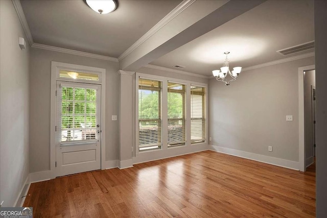 doorway to outside featuring visible vents, wood finished floors, baseboards, an inviting chandelier, and ornamental molding