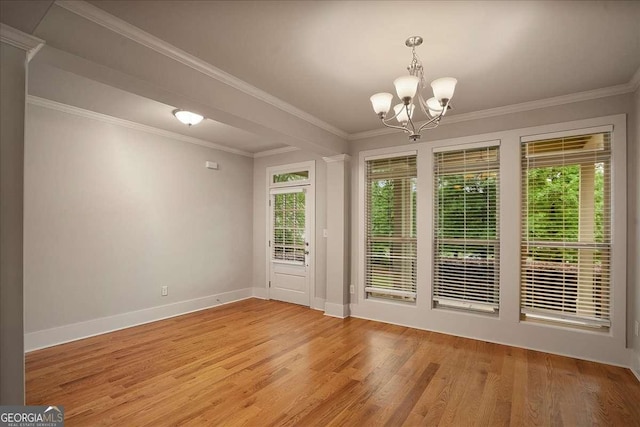 interior space with an inviting chandelier, baseboards, ornamental molding, and light wood-type flooring