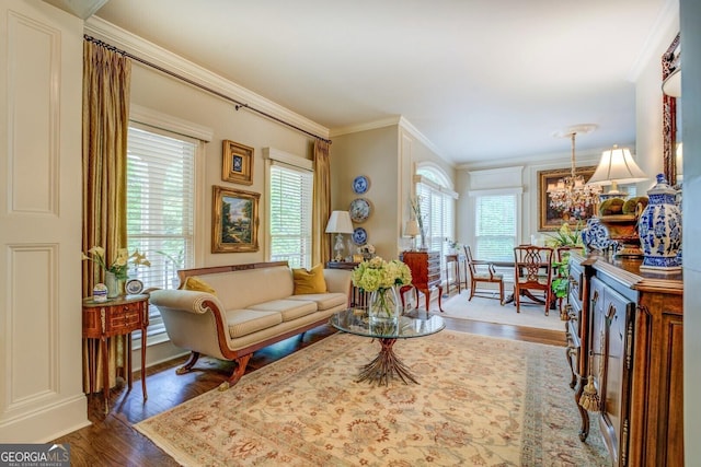 living area with crown molding, wood finished floors, and a notable chandelier