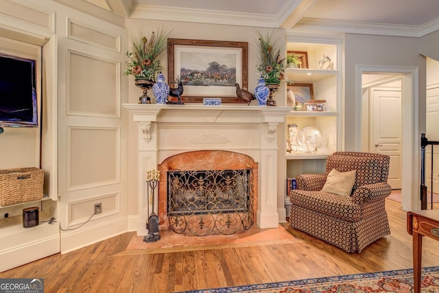 living area with crown molding, light wood finished floors, and a fireplace