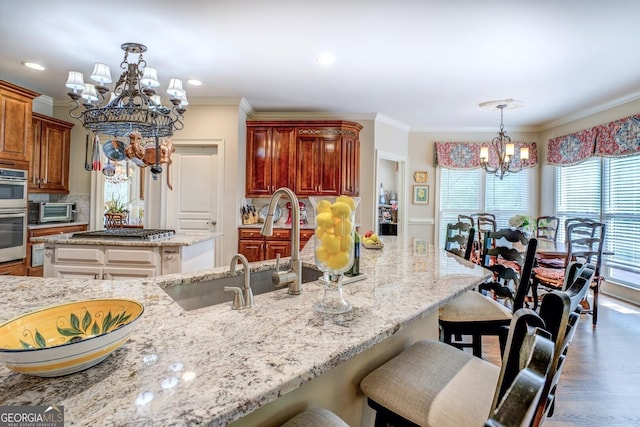 kitchen with a breakfast bar area, decorative light fixtures, appliances with stainless steel finishes, an inviting chandelier, and ornamental molding