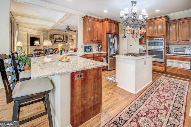 kitchen with light stone countertops, appliances with stainless steel finishes, a sink, and a warming drawer