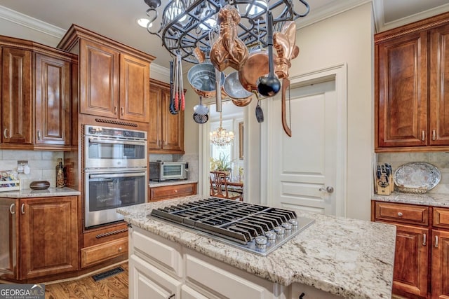 kitchen featuring decorative backsplash, a toaster, light stone countertops, a chandelier, and stainless steel appliances