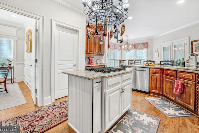 kitchen featuring crown molding, a sink, a chandelier, stainless steel appliances, and a kitchen island