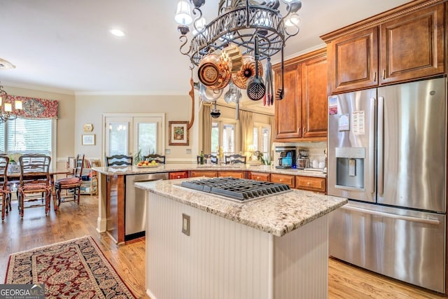 kitchen with light stone countertops, a notable chandelier, a center island, stainless steel appliances, and a peninsula