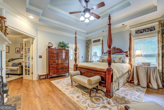 bedroom featuring crown molding, baseboards, recessed lighting, a tray ceiling, and light wood-style flooring