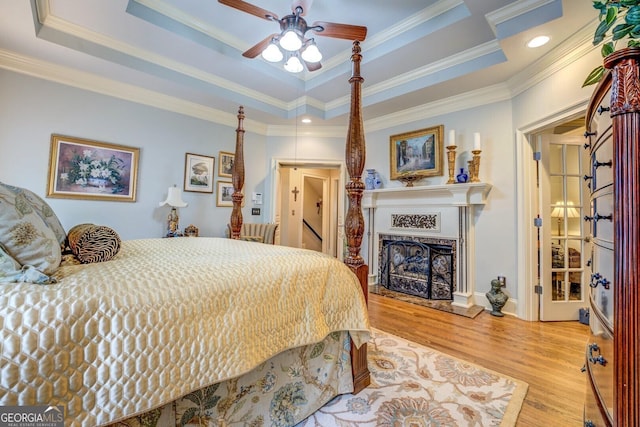 bedroom with crown molding, wood finished floors, and a tray ceiling