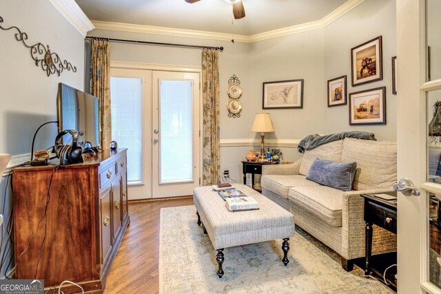 living area featuring light wood-type flooring, ornamental molding, and ceiling fan