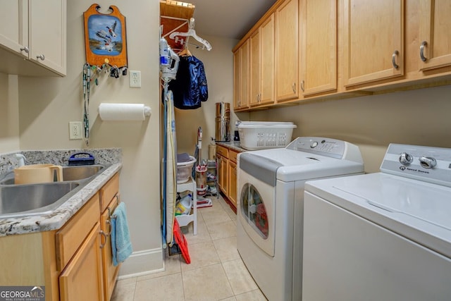 washroom with a sink, cabinet space, light tile patterned floors, and washing machine and clothes dryer