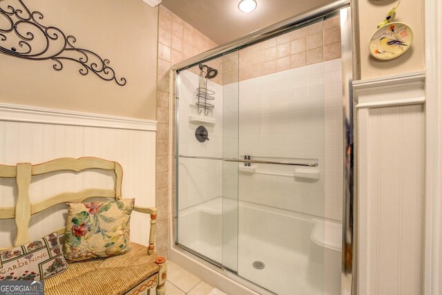 full bath featuring a wainscoted wall, tile patterned flooring, and a stall shower
