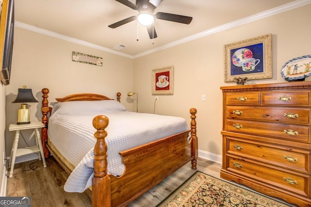 bedroom featuring crown molding, baseboards, wood finished floors, and visible vents