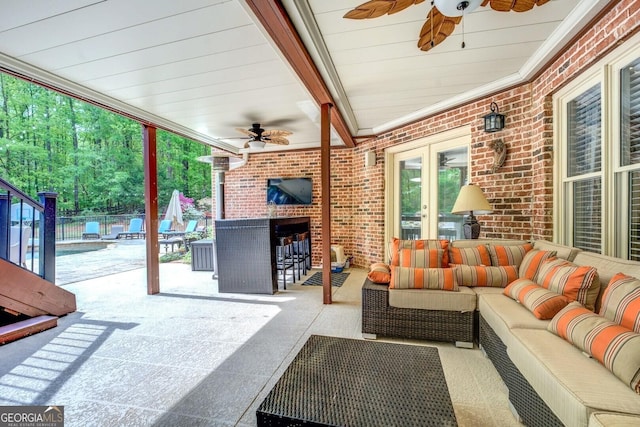 view of patio / terrace featuring a ceiling fan, an outdoor living space with a fireplace, fence, and french doors