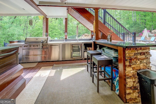 view of patio / terrace featuring outdoor wet bar, exterior kitchen, beverage cooler, area for grilling, and stairway