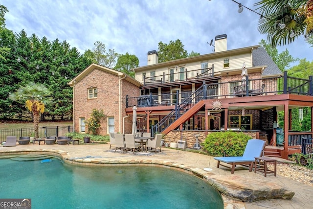 back of property featuring a chimney, a deck, and brick siding