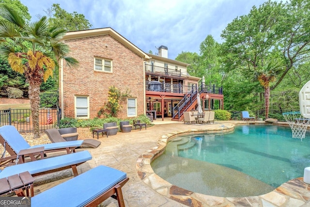 view of swimming pool featuring fence, a deck, a patio, a fenced in pool, and stairway