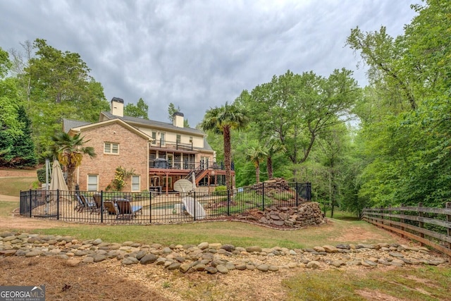 rear view of property with a chimney, a balcony, a fenced backyard, and a patio area