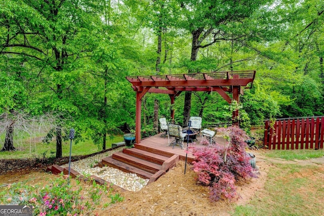 view of yard with a deck, fence, a forest view, and a pergola