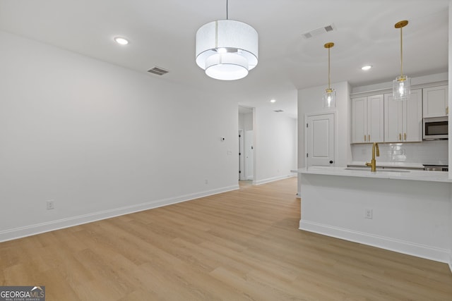 1488 Campbell Rd, Covington, GA 30014 - kitchen featuring light countertops, stainless steel microwave, a sink, and light wood-style flooring