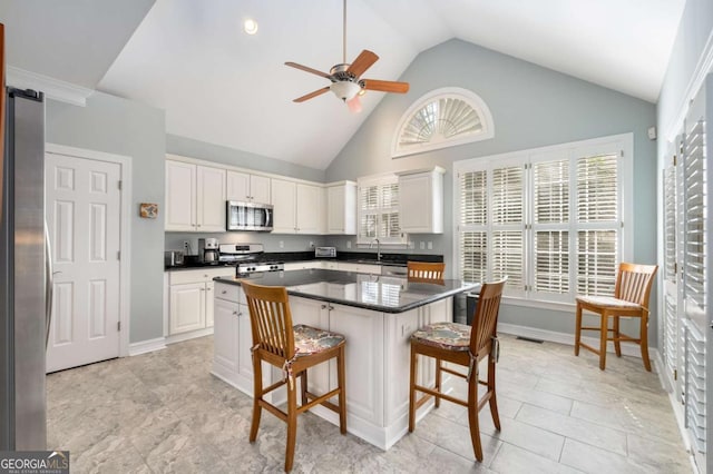 5 Renfroe Ct, Decatur, GA 30030 - kitchen featuring appliances with stainless steel finishes, a kitchen breakfast bar, dark countertops, ceiling fan, and a center island