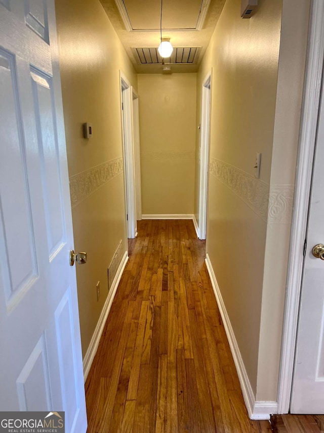 corridor with hardwood / wood-style flooring, visible vents, and attic access