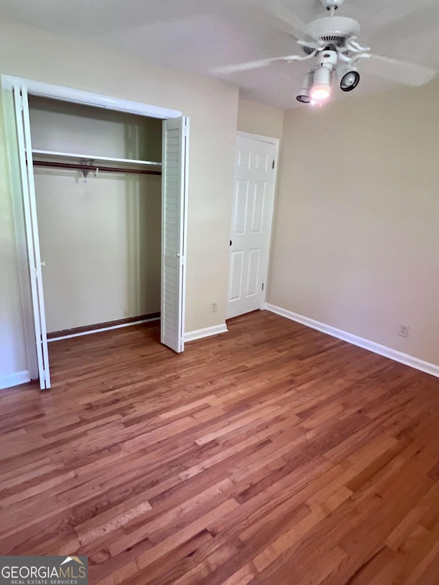 unfurnished bedroom featuring baseboards, ceiling fan, wood finished floors, and a closet