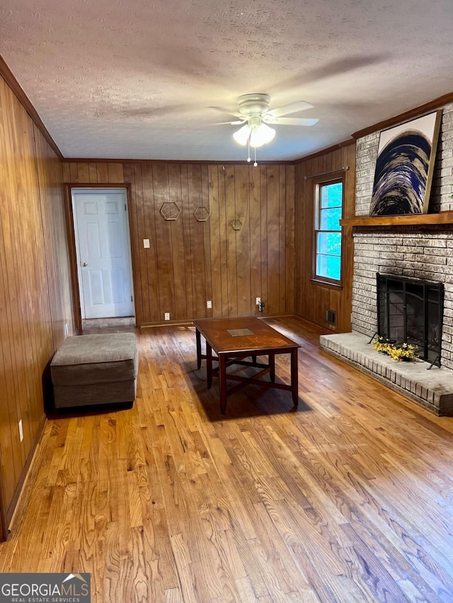 unfurnished living room featuring light wood-style floors, a textured ceiling, ceiling fan, and wooden walls