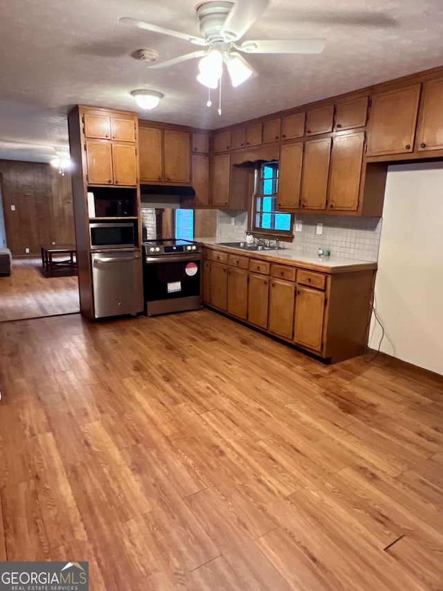 kitchen featuring brown cabinets, appliances with stainless steel finishes, a sink, and light wood-type flooring