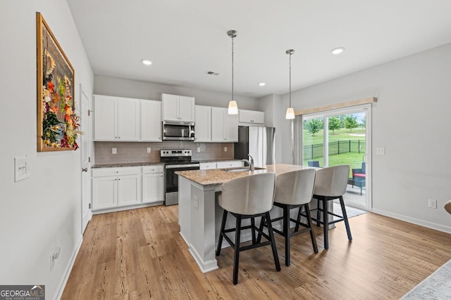 181 Sweet Briar Way, Homer, GA 30547 - kitchen featuring appliances with stainless steel finishes, a center island with sink, a breakfast bar area, white cabinetry, and light wood finished floors