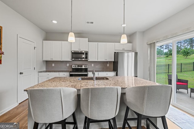 181 Sweet Briar Way, Homer, GA 30547 - kitchen featuring appliances with stainless steel finishes, decorative backsplash, a kitchen island with sink, wood finished floors, and recessed lighting