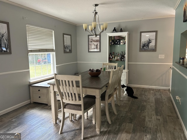 dining space with baseboards, ornamental molding, wood finished floors, and a chandelier