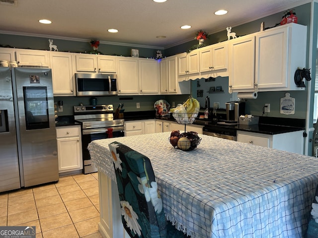 kitchen with crown molding, white cabinetry, light tile patterned flooring, and stainless steel appliances