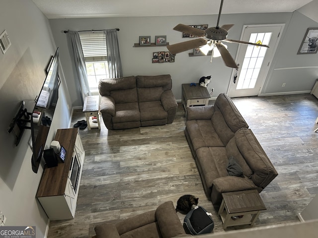 living room with a ceiling fan, wood finished floors, and a wealth of natural light
