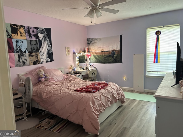 bedroom featuring baseboards, a textured ceiling, ceiling fan, and wood finished floors