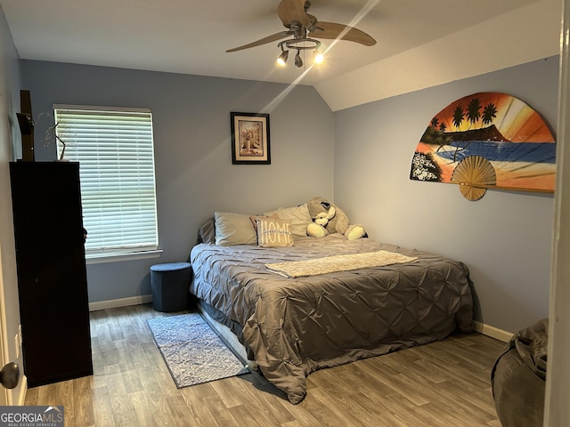 bedroom with a ceiling fan, baseboards, vaulted ceiling, and wood finished floors