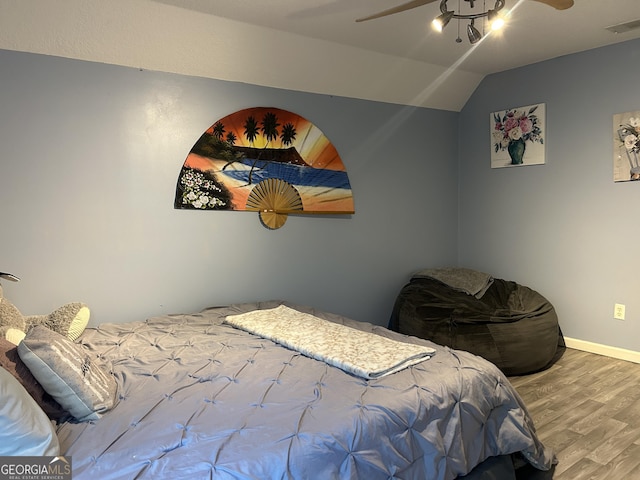 bedroom featuring visible vents, a ceiling fan, baseboards, wood finished floors, and vaulted ceiling