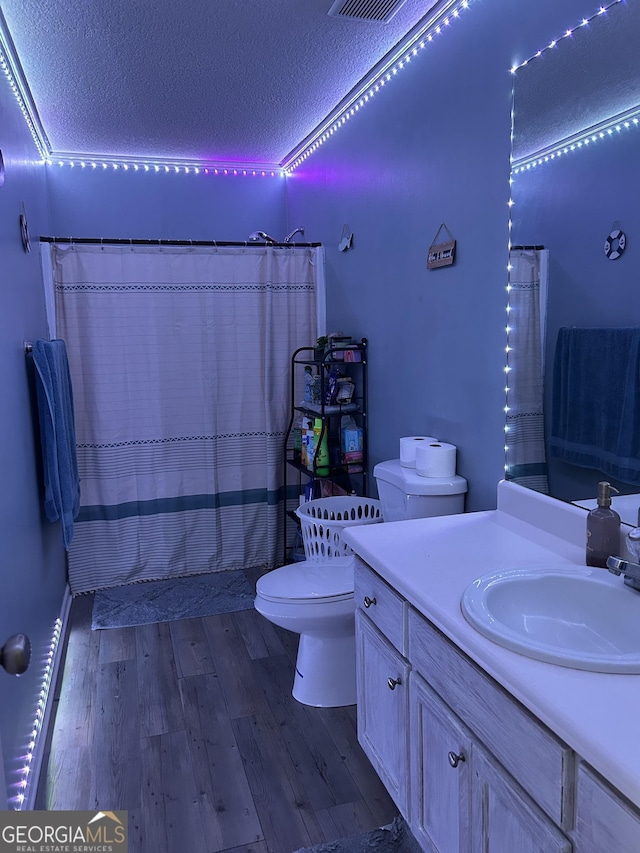 bathroom with vanity, wood finished floors, toilet, a shower with shower curtain, and a textured ceiling