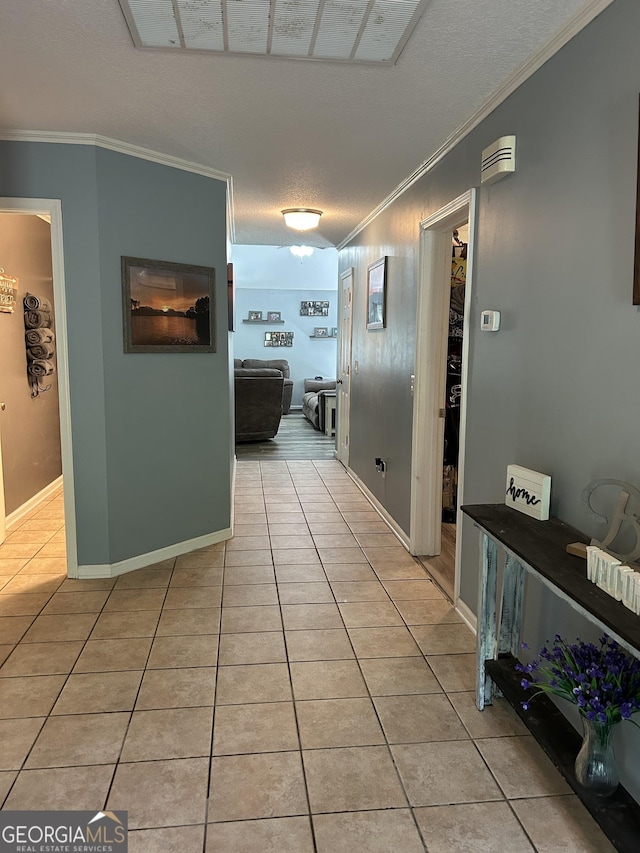 hall featuring baseboards, ornamental molding, and light tile patterned floors