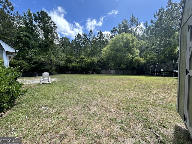 view of yard featuring fence and a trampoline