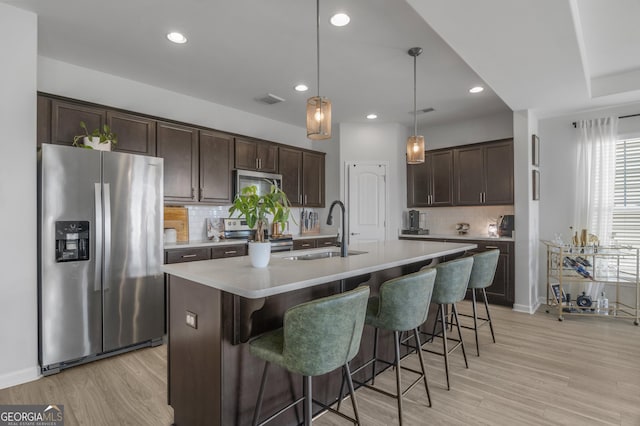 234 Lakepointe Dr, Savannah, GA 31407 - kitchen with decorative backsplash, dark brown cabinets, light wood-type flooring, a sink, and appliances with stainless steel finishes