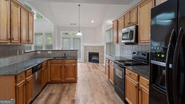 kitchen featuring plenty of natural light, backsplash, a tiled fireplace, a sink, and black appliances
