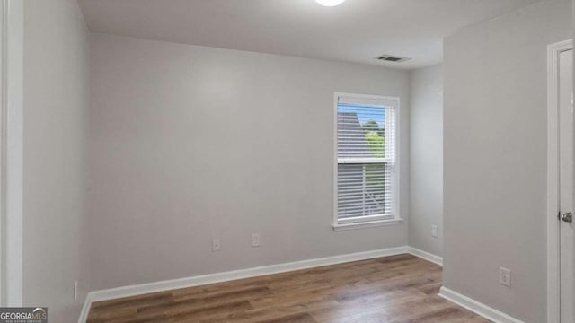 unfurnished room with baseboards, wood finished floors, and visible vents
