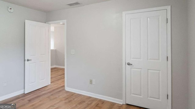 unfurnished bedroom featuring baseboards, light wood-type flooring, and visible vents