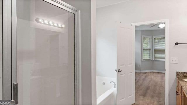 full bathroom with a stall shower, wood finished floors, a bath, and vanity