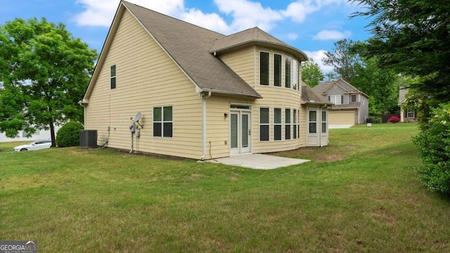 rear view of property with a yard, cooling unit, and a shingled roof