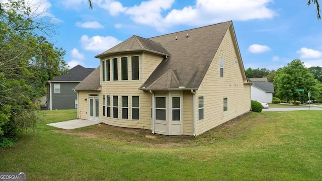 rear view of property with a shingled roof and a yard