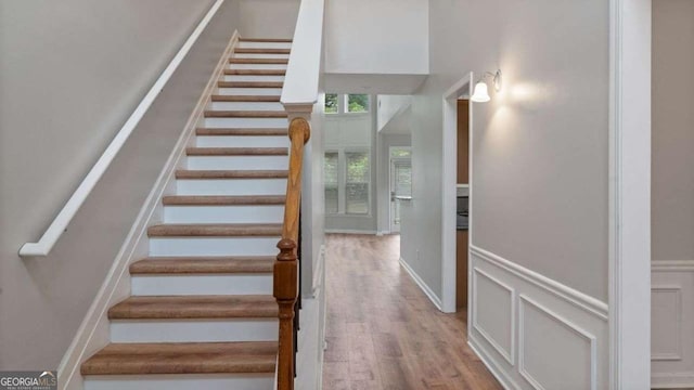stairs with wainscoting and wood finished floors
