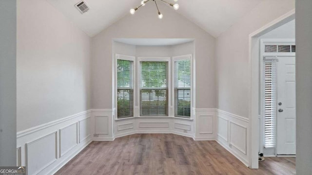 spare room featuring a decorative wall, an inviting chandelier, and a wainscoted wall