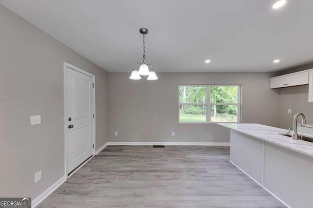 unfurnished dining area with baseboards, recessed lighting, and light wood-style flooring
