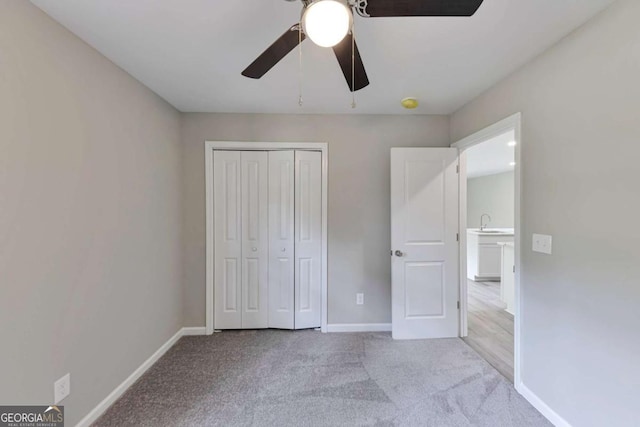 unfurnished bedroom featuring ceiling fan, a sink, baseboards, a closet, and carpet flooring