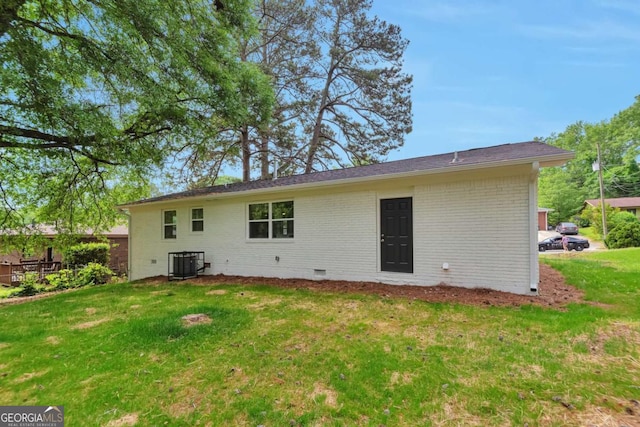 rear view of house featuring brick siding, a yard, crawl space, and cooling unit